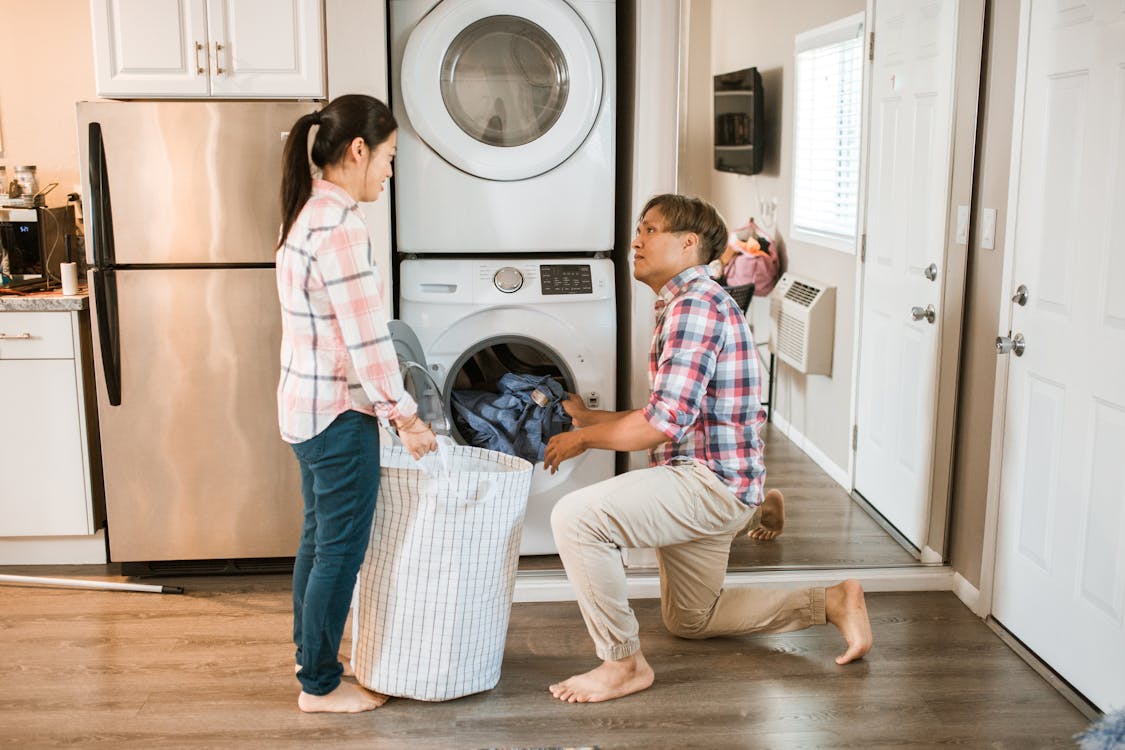 Couple loading a washing machine at home